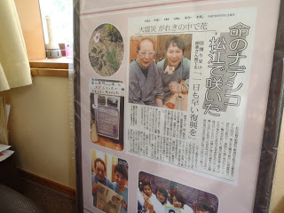 「命のナデシコ松江で咲いた」と書かれた新聞記事などの切り抜きが飾られている写真