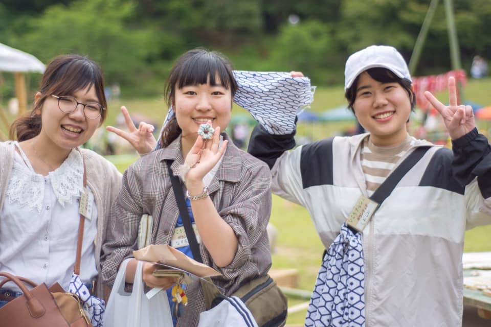 屋外の緑豊かな場所で楽しそうにポーズをとる3人の女性の写真