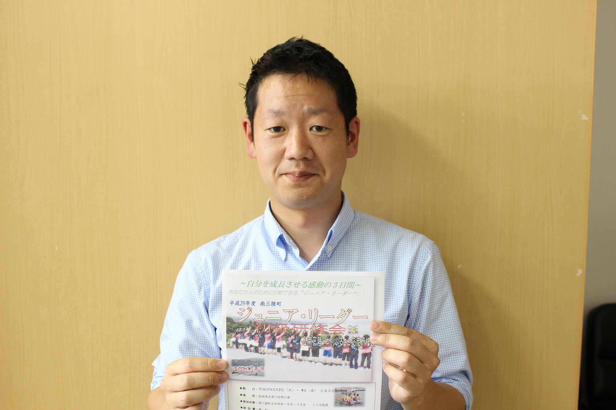 「ジュニア・リーダー」と書かれたチラシのようなものをカメラに向けて見せている大塚茂之さんの写真
