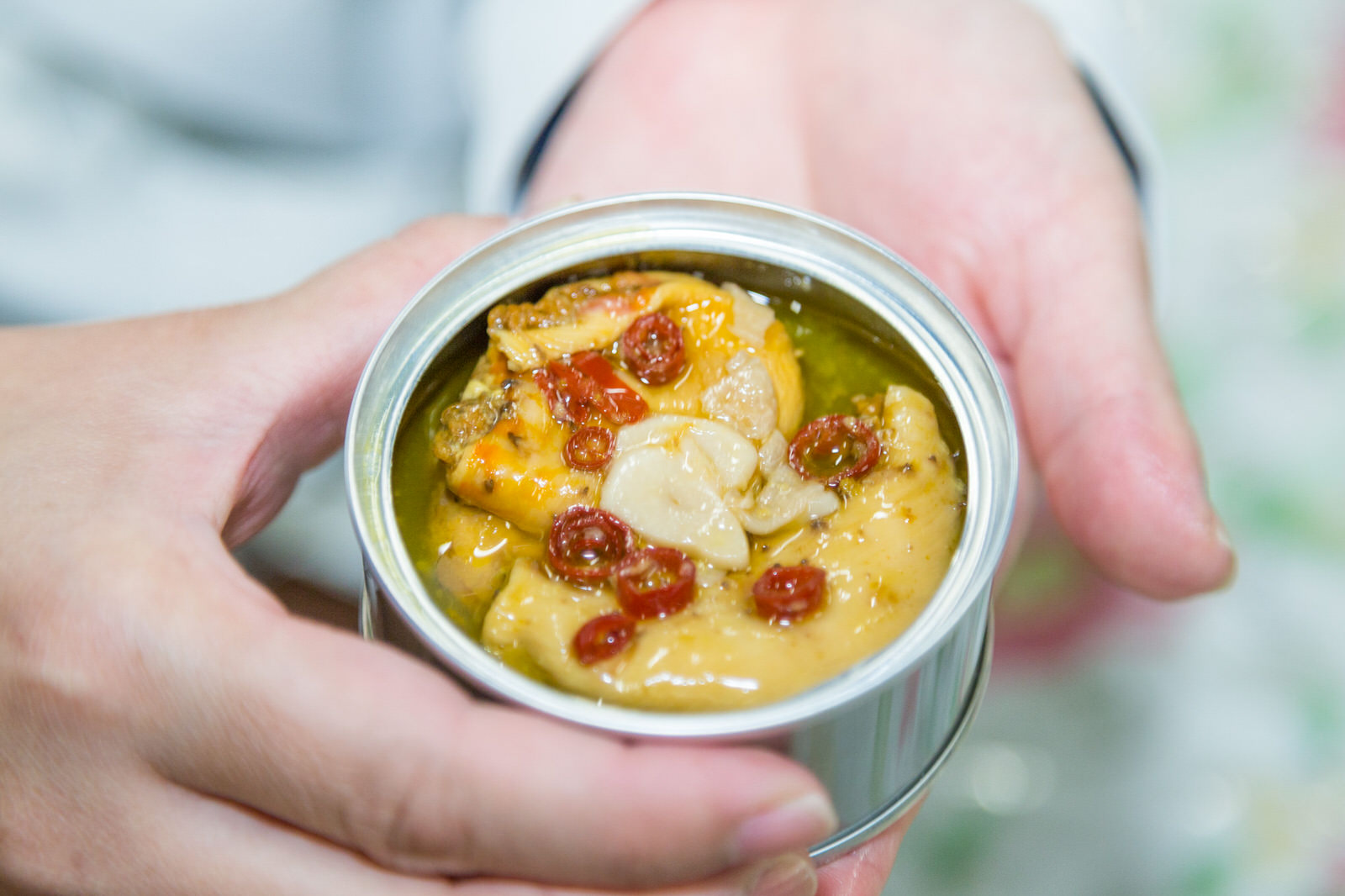 缶詰の中に、スライスガーリックと鷹の爪と一緒にオイル漬けになった大きなタコの身が入っているタコのアヒージョの缶詰の写真