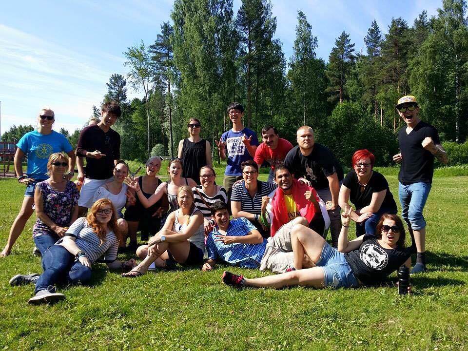 緑豊かな芝生の広場で、寝そべったりしゃがんだりと思い思いのポーズをとった外国人の人々と佐藤さんが写った集合写真