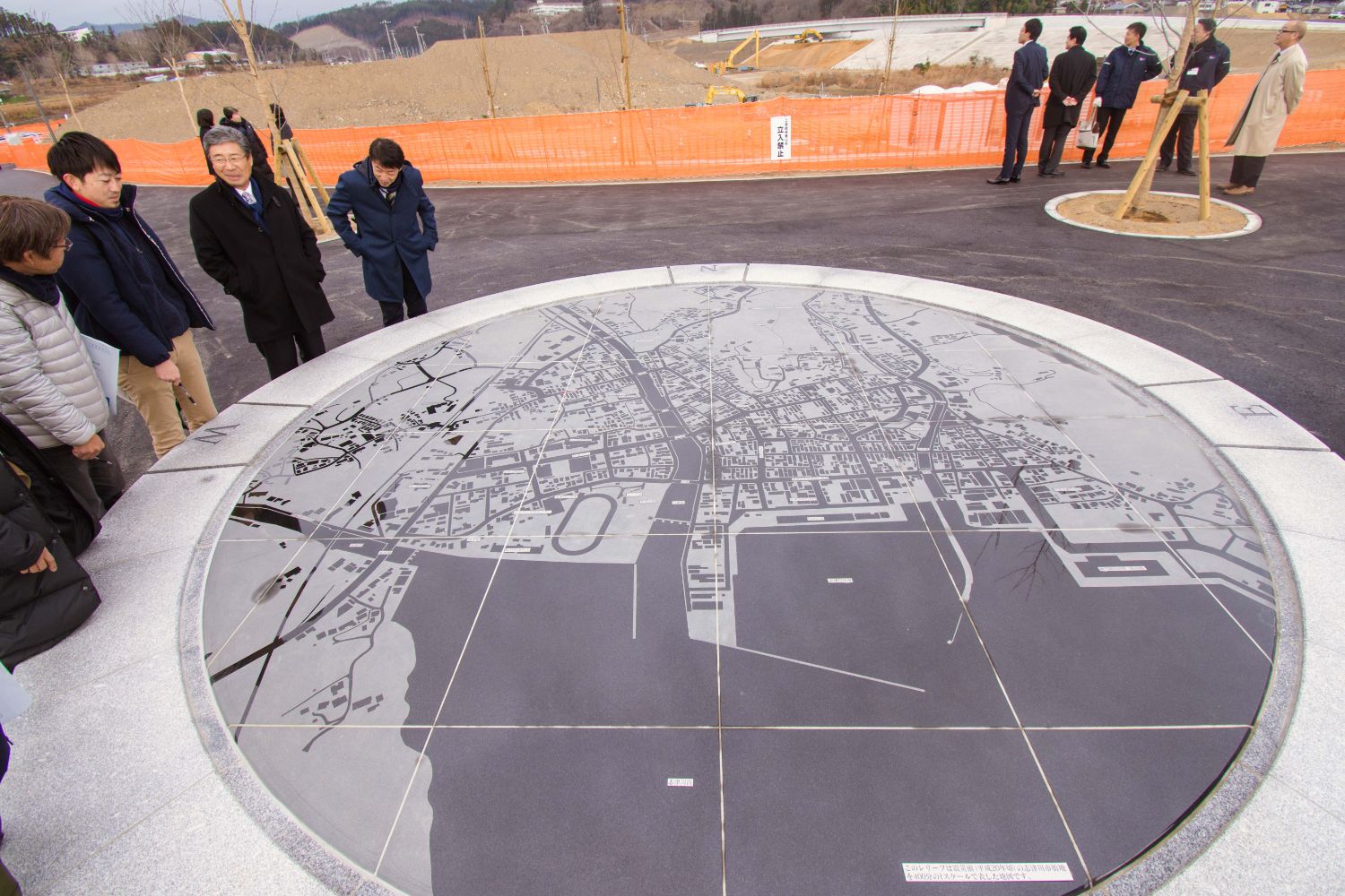 屋外に設置された大きな円形の、地図を石板に刻んだメモリアルレリーフを見下ろしている人々の写真