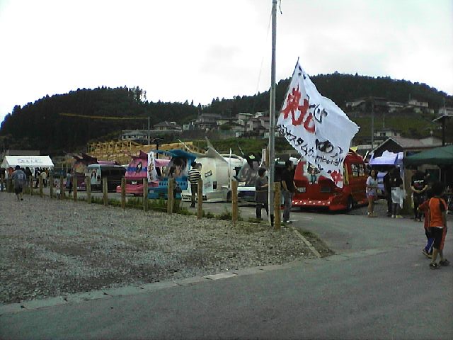 東北と書かれた大きな白い旗が掲げられた会場に多くの色鮮やかなカスタムカーが並び、見物客が集まっている様子を写した写真