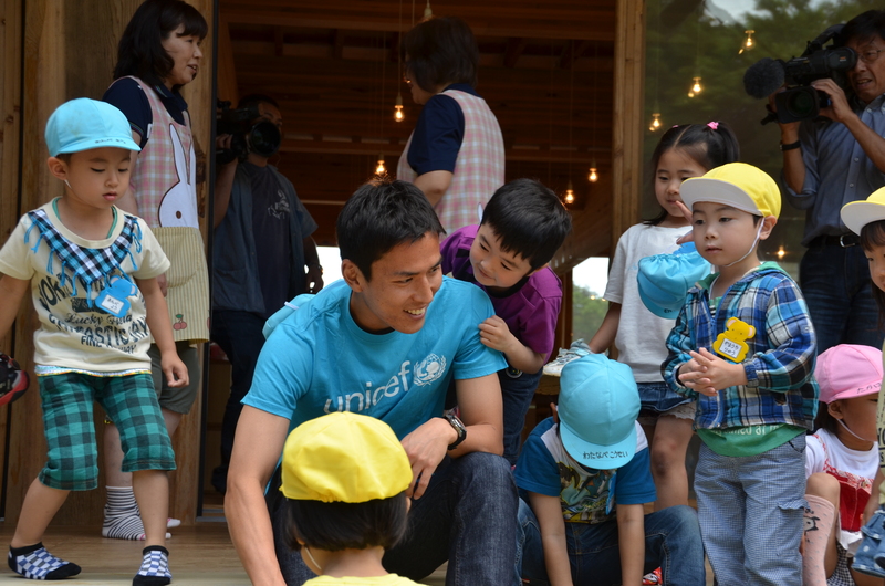 長谷部誠選手が園児たちに囲まれて、笑顔で触れ合っている様子を写した写真