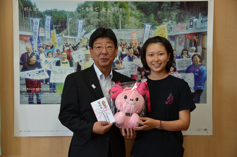 町長ときみつ少年少女合唱団の関係者の女性が並び、寄付金ときみぴょんのぬいぐるみを持って笑顔で写っている記念写真