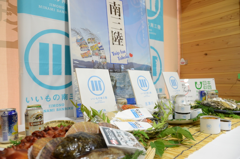 南三陸の水産物や缶詰などが並べられ、「いいもの南三陸」や「Trip for Tohoku」と書かれたパネルが立てられている「復興応援キリン絆プロジェクト」の南三陸ブースの様子を写した写真