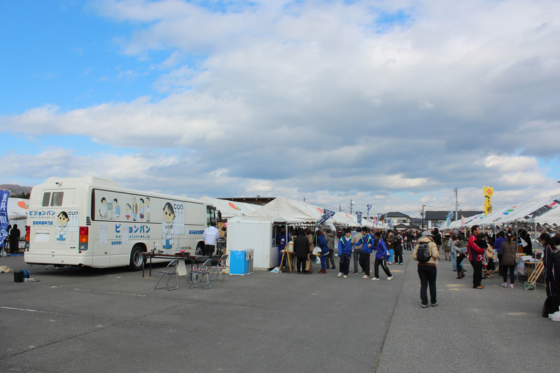 広い駐車場に白いテントが立ち並び、多くの人が行き交う、にぎやかな志津川湾鮭・いくらまつり福興市の写真
