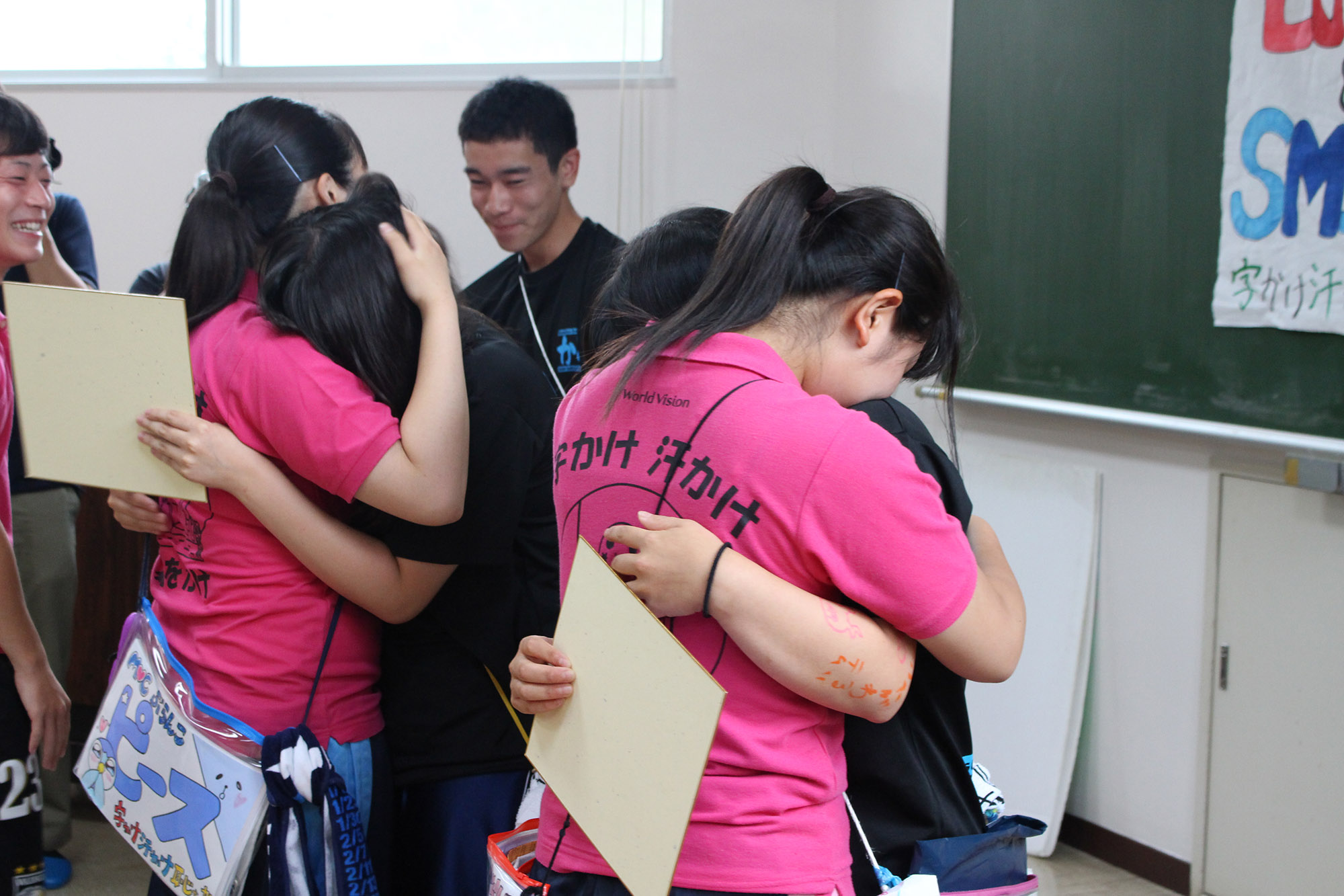 黒いTシャツを着たジュニアリーダーとピンク色のTシャツを着たジュニアリーダーたちがお互いに抱き合い別れを惜しんでいる様子の写真