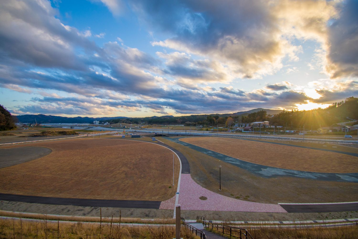 階段を下りた先に広がる、中心部と外側を取り囲むように遊歩道がレイアウトされた広大な敷地の松原公園の写真