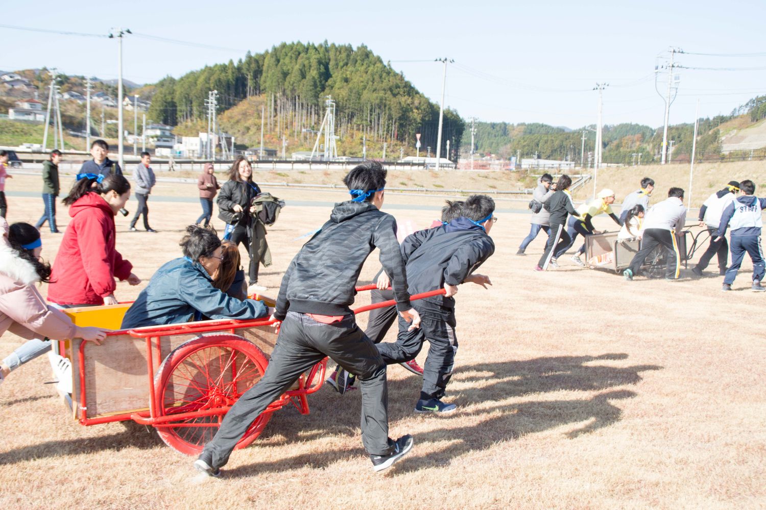 メンバーをリヤカーに乗せ、5～6人ほどのチームで運びリレーを行っている様子の写真