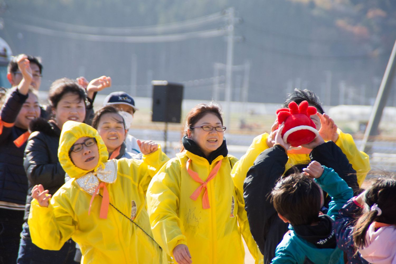 子ども達や黄色のジャケットを着たオレンジ色の鉢巻を首に巻いたメンバーが縦一列に並び、オクトパス君を運んでいるリレーの様子の写真