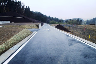 新しく舗装された道路がまっすぐ伸び、両側にまだ建物のない宅地が整地されている写真