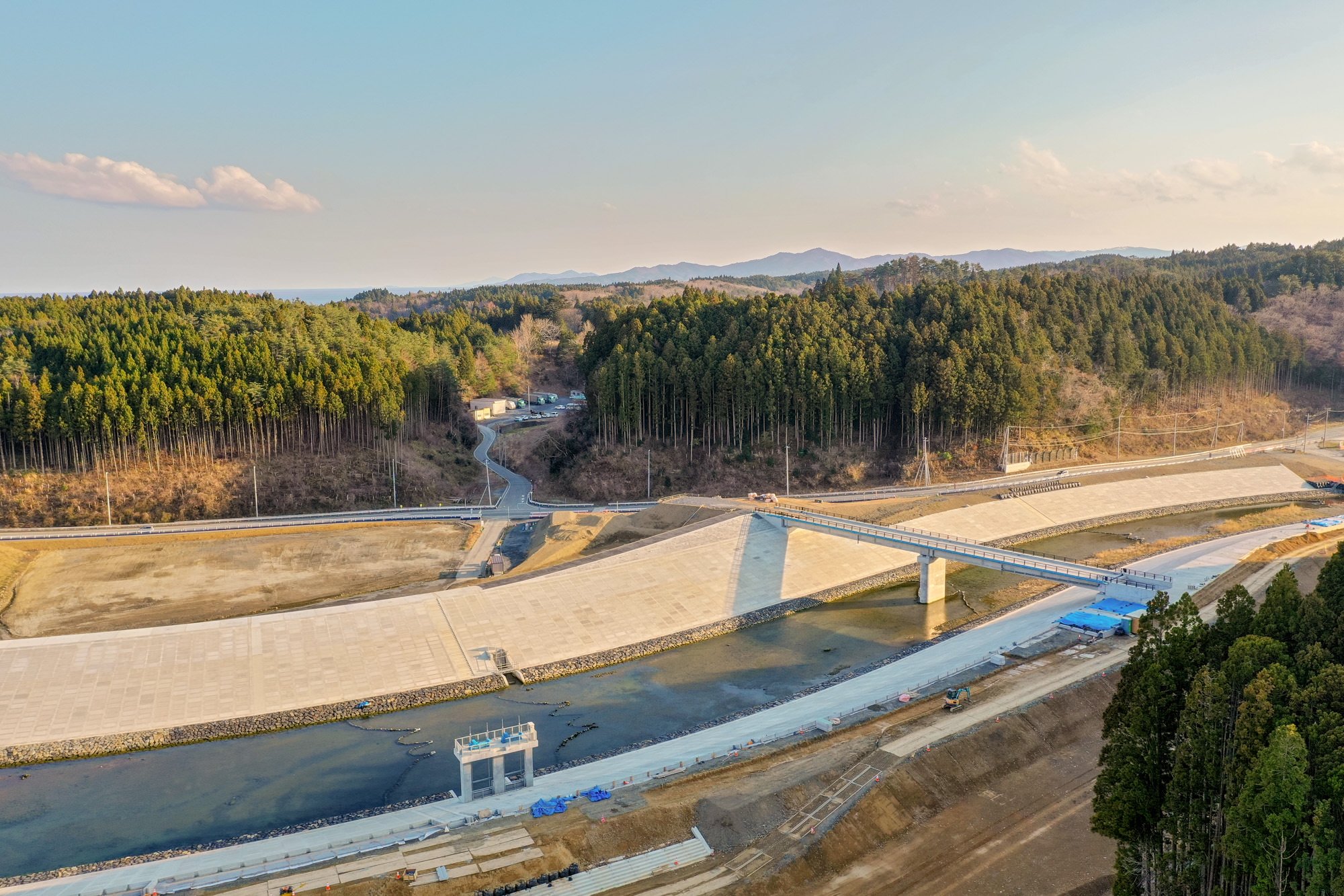 広々とした川の上に橋が架かり、その周囲には道路や建物、緑地などが広がる様子を空から撮影した川と橋の写真