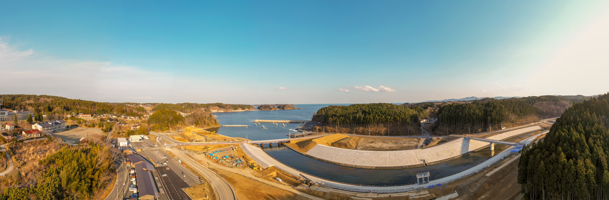 海岸沿いに広がる町とその周辺の建物や道路、海の様子を空から広く見渡すように撮影した海辺の町の写真