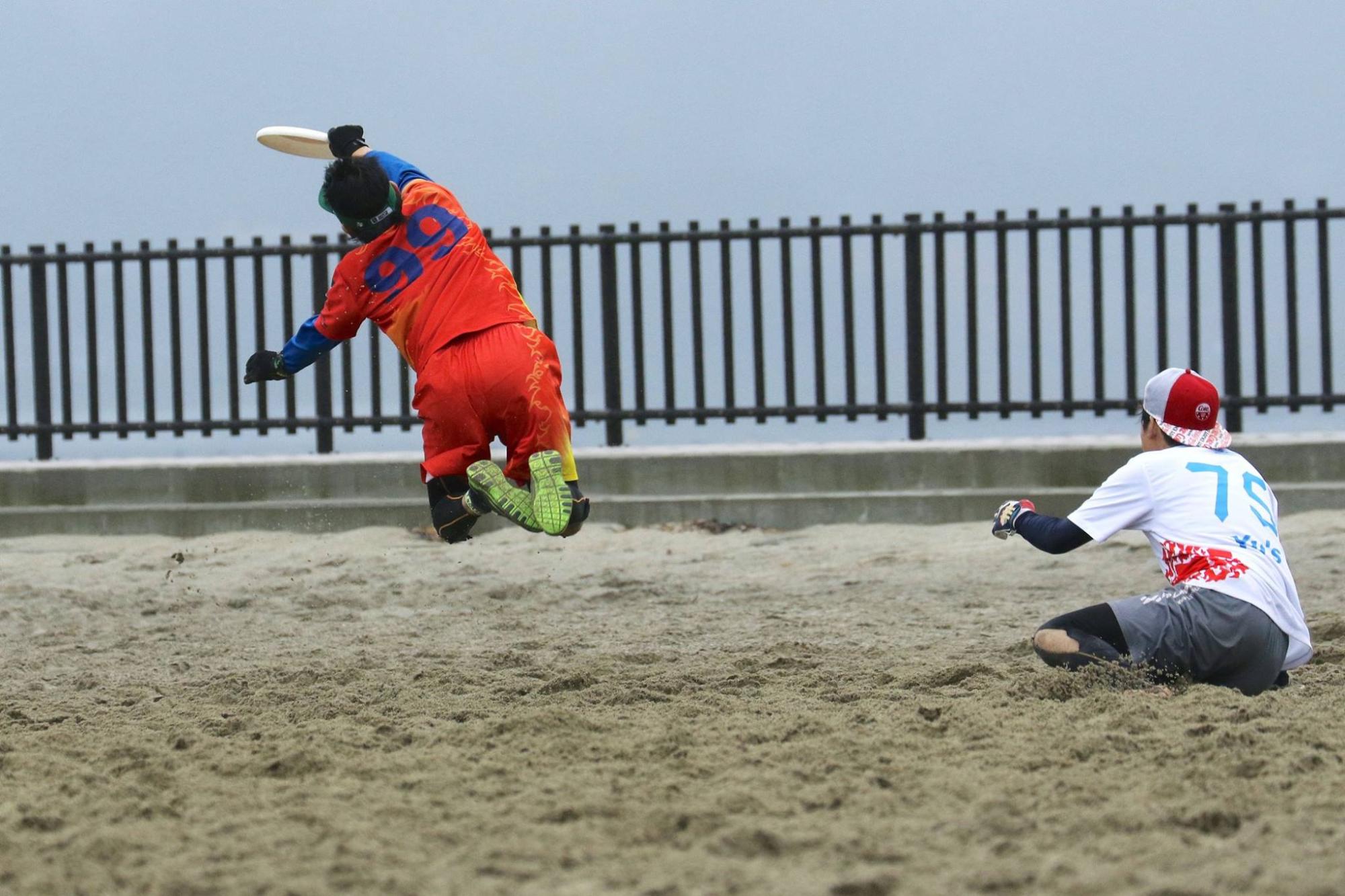 オレンジのユニフォーム姿の男性が空中でディスクをキャッチする瞬間の写真