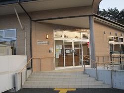 タイル張りのスロープと手すりが備えられた玄関があり、ガラス扉の奥に受付カウンターが見える戸倉地区放課後児童クラブ入口の写真