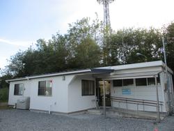 木々を背にした白い平屋建ての建物で、手前にはスロープと手すりが設けられたバリアフリー対応の入口がある歌津地区放課後児童クラブの写真