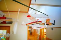 保育園内の廊下の天井に吊り下げられた紙飛行機の模型をアップで撮影した写真