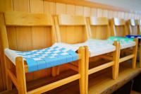 色とりどりの布で編まれた座面が付けられている子ども用の木製椅子が横一列に並んでいる写真