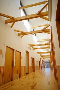 天井の梁が特徴的で、木のぬくもりを感じられる長い廊下の写真