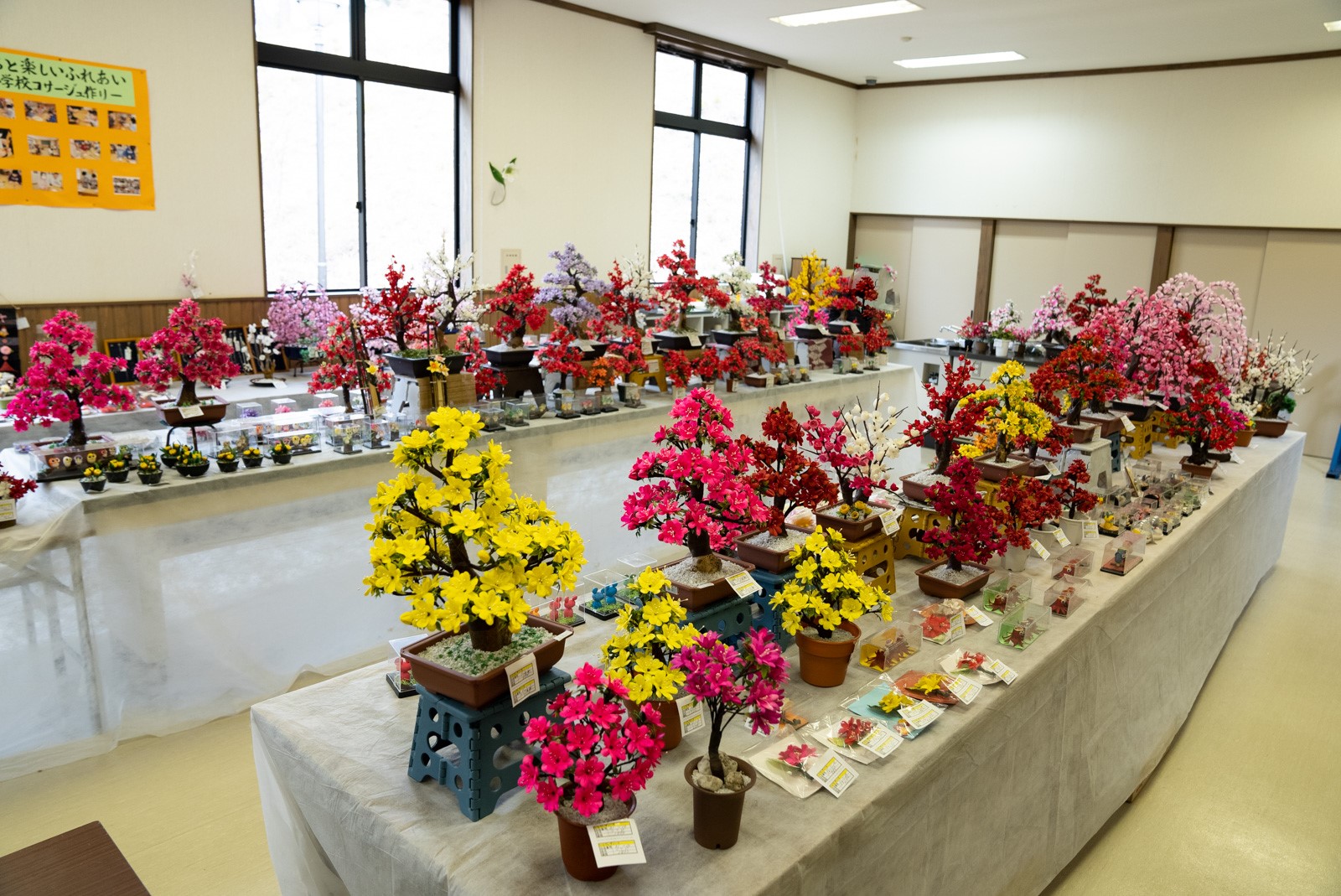 黄色やピンクなどの鮮やかな造花がたくさん展示されているイベント会場の様子の写真