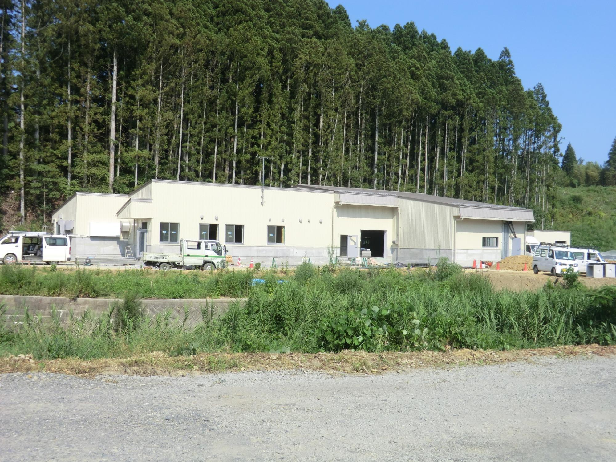 建物の前には工事用のトラックや作業車が停まっている建設途中の写真