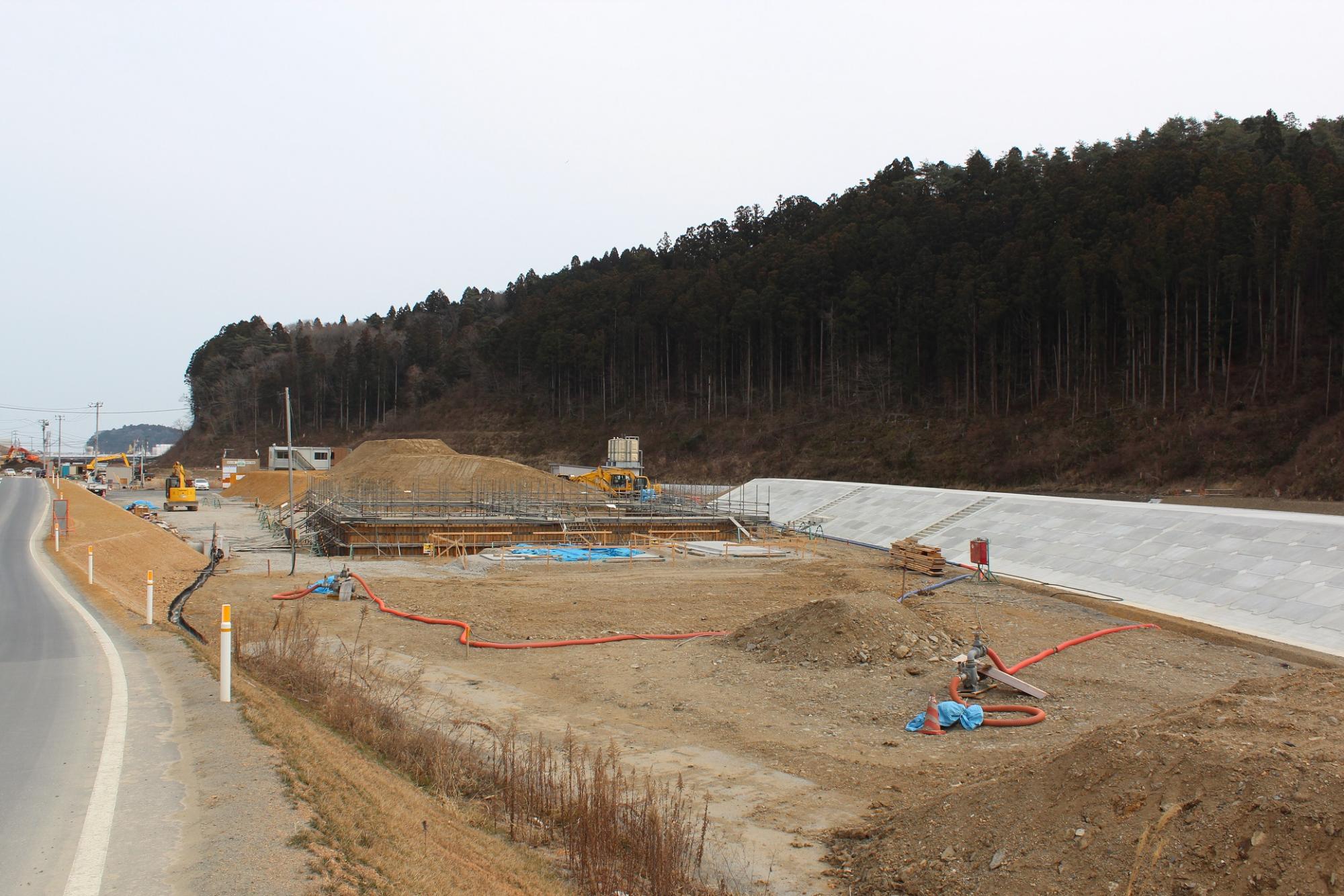 造成地に組まれた足場と基礎工事中の構造物を中心に、周囲に土砂や資材が広がっている水尻ふ化場の建設中写真