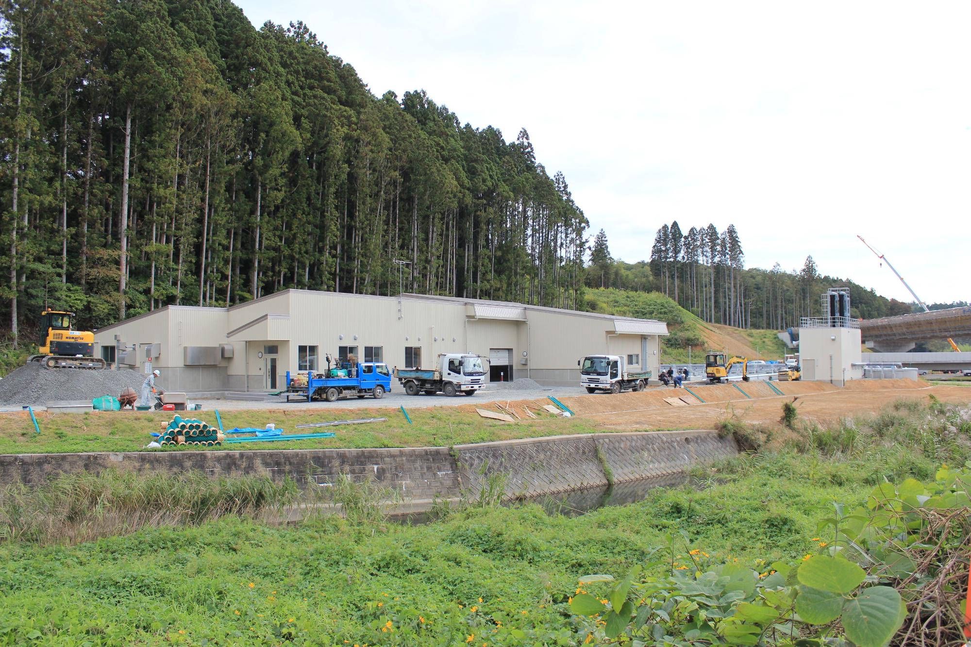 建物の周囲で工事車両が作業を行っており、外構工事や整地作業が進行中の様子を撮影した写真