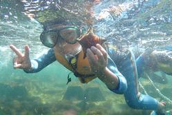 海の中のシュノーケリング中に左手にヒトデを持ちピースサインをしている子どもの写真