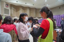 客席近くで赤いビブスを着た係の人とカードをやり取りする子どもたちの写真