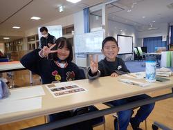 机に座ってピースをしている男の子と女の子の写真