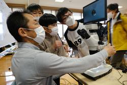 教室で顕微鏡を使って観察している男性講師や子どもたちの写真