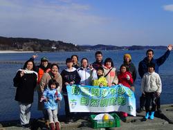 海を背景に自然観察隊の旗を持って記念写真を撮っている子供たちの写真