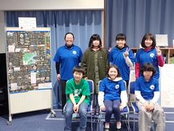 展示した壁新聞の前に2列に並んだメンバーが記念写真を撮っている写真