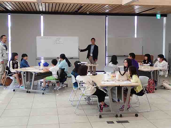 室内で講師がホワイトボードを使って子どもたちに話をしているオリエンテーションの様子の写真