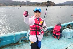 手に釣った魚を持ってポーズをとっている女の子の写真