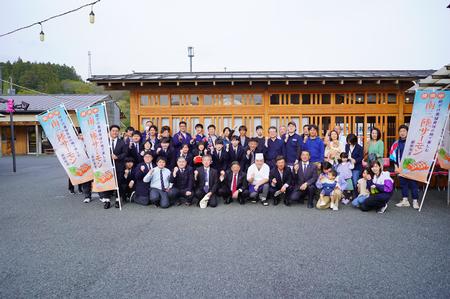 「南三陸サーモン」と書かれたのぼり旗を持った人が両側に立ち、中央に多くの関係者の方が集まり記念撮影をしている写真